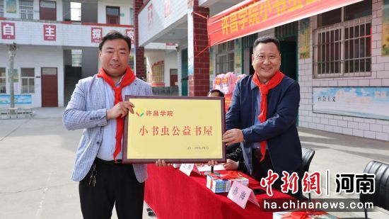 图为澳门所有的游戏网站大全党委副书记孙海(右1)将“小书虫”公益书屋的牌匾交到关爷庙小学校长杨少许手中。